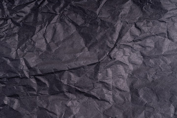Dark wrinkled creased black paper poster texture. Blank creased crumpled grainy paper textured surface. Smudged grungy cardboard with fiber. Close up. Material tissue for packing