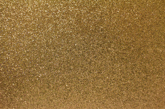 Sparkling gold glitter texture background with defocused bokeh
