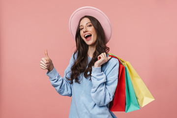 Image of young woman gesturing thumb up while holding shopping bags