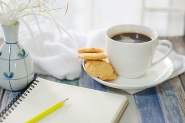 Cup of hot coffee with .butter cookies,  notebook and flower on a wooden table holiday home vacation ideas