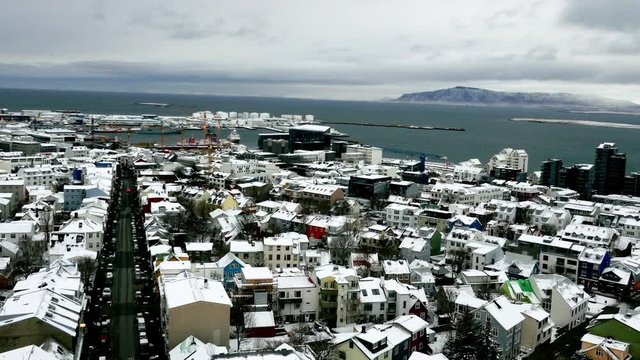 Aerial long shot cityscape of snowy Reykjavik with Mount Esja at the background during winter