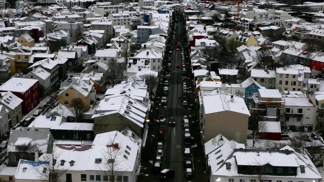 Aerial long shot cityscape of snowy Reykjavik with Mount Esja at the background during winter