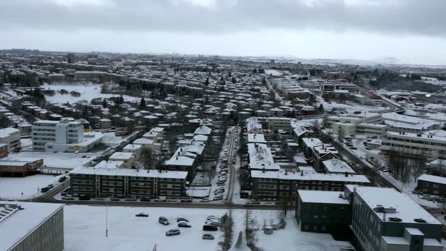 Aerial long shot cityscape of snowy Reykjavik with Mount Esja at the background during winter