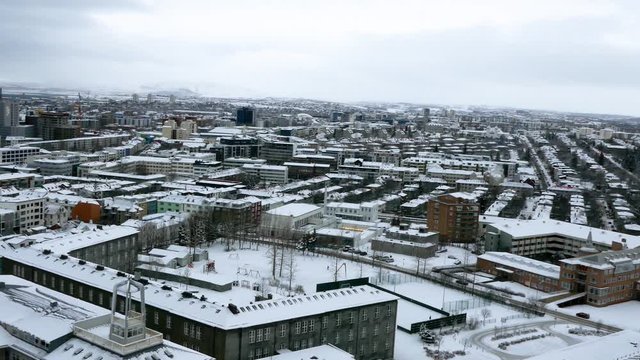 Aerial long shot cityscape of snowy Reykjavik with Mount Esja at the background during winter