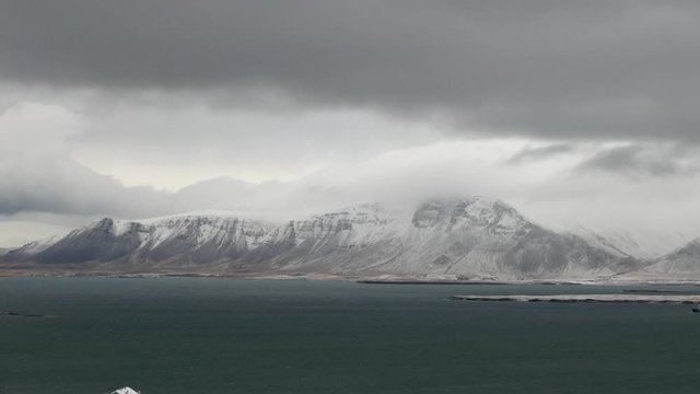 Aerial long shot of Reykjavik snowy Esja mountain with a cloudy sky