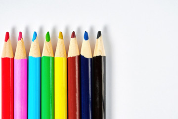 Rainbow colorful pencils in a row on the white paper, flat lay background. Copy space for your text