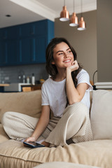 Obraz premium Beautiful young brunette woman relaxing on a couch at home