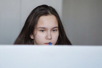 Teenager girl at a table with a white laptop.