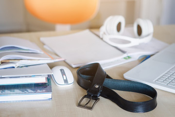 Belt on the table with a mouse and white laptop.