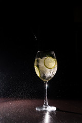 refreshing cocktail on a neutral black background with flying splashes in the air