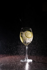 refreshing cocktail on a neutral black background with flying splashes in the air