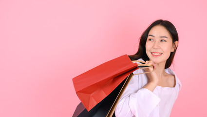 Portrait of beautiful asian girl holding shopping bags, on pink background