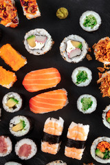 Large sushi set, overhead shot on a black background. Many different maki, nigiri and rolls