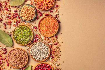 Legumes assortment, shot from above on a rustic brown background with copy space. Lentils, soybeans, chickpeas, red kidney beans, a vatiety of pulses