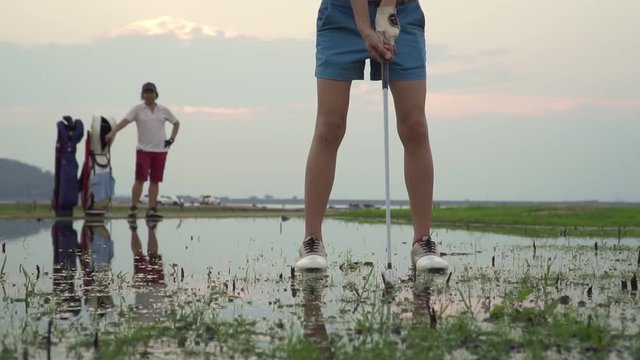 Footage B Roll Of Slow Motion Couple Lover In Action Of Playing Golf Together. Golf Ball Away From The Rough To Fairway, Difficult Time Stay Together In The Family Course. Beautiful Nature Silhouette.