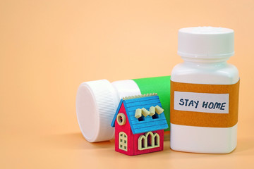 Medicine bottle with miniature wooden home. COVID-19 coronavirus concept photography : Stay Home the Magical medicine for saving life, stay safe. Selective focus with copy space.