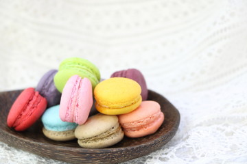Fototapeta na wymiar Close up colorful fresh sweet cake macarons on wooden ladle on white fabric background, have copy space for put text.