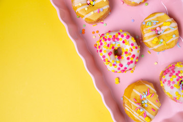 Sprinkled mini donuts on a pink serving tray on a colorful background