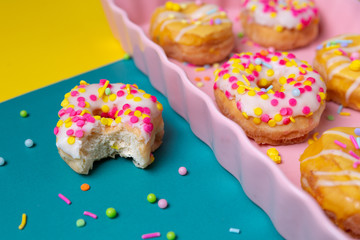 Sprinkled mini donuts on a pink serving tray on a colorful background