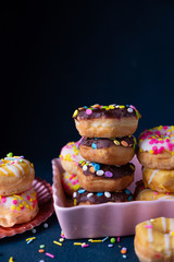Sprinkled mini donuts stacked with a dark background