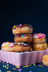 Sprinkled mini donuts stacked with a dark background