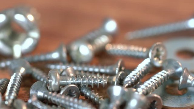 The Bunch of Steel Screws on Wooden Table. Screw Production, Heap of Metal Details, Close Up shot