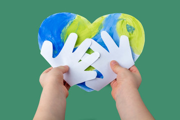 The Concept of DIY and children creativity. Step by step instruction: make applique from paper. Step 4 The child hands holds a finished craft Planet earth in the form of a heart. World Earth Day