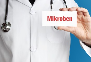 Mikroben. Arzt im Kittel hält Visitenkarte hoch. Der Begriff Mikroben steht im Schild. Symbol für...