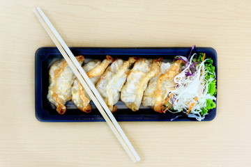 Fried Gyoza, Japanese dish consisting of wonton wrappers stuffed with pork and cabbage, eat with soy sauce, on wood table
