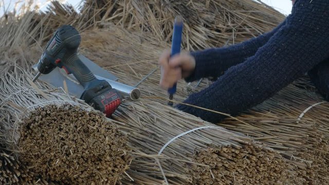 A Thatcher  Is Using An Automatic Tie Wire Twister For Tying Up Reeds To Be Used In Thatching-closeup shot