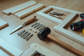Top view of furniture assembly parts and wood work tools on wooden floor for DIY do it yourself