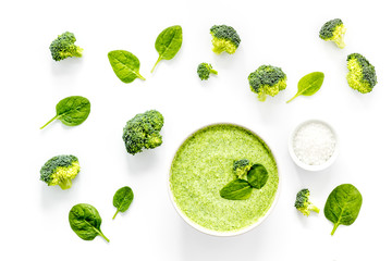 Broccoli and spinach cream soup on white desk from above. Vegetable pattern