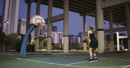 Girl shooting basketball hoop at night - Powered by Adobe
