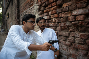 An young Indian Bengali detective and his assistant with traditional wear going to attack with a gun in a winter morning in a crime scene.
