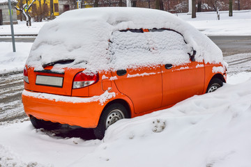 orange small car covered with white snow