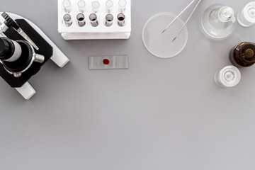 Clinical science research with microscope. Laboratory equipment on grey background top view copy space