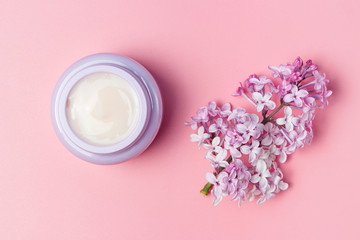 Open jar with cream on pink background, top view