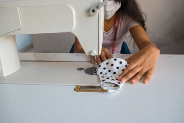 A close-up of the seamstress sitting and sewing. Seamstress working on the sewing machine. Tailor making a garment.