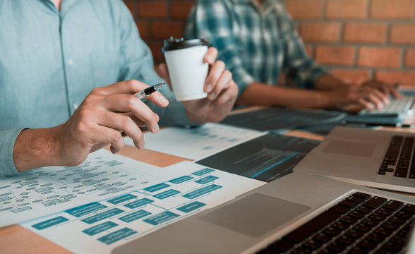 Working in the morning with businessmen are dipping coffee that works with software developers to analysis together the code written in the program on the computer.