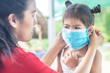 The mother wears a doctor's mask for her daughter to prevent the coronary virus that is spreading throughout the world and can also prevent other bacteria from entering the body