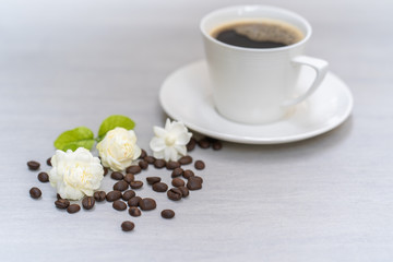 Jasmine flower and cup coffee on textured tile tray. 
