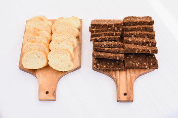 Two types of Fresh sliced french and brown breads on a wooden cutting board isolated on white, fresh baked, delivery option, restaurant website menu, take out food, fresh loaf on a cutting board