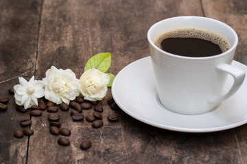 Cup coffee and jasmine flower on old wooden plate.