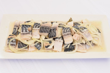 Sliced marinated herring on a white plate, isolated white background, mediterranean food delivery appetizer, take out, original healthy food, gourmet menu option 