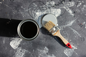 Painters work with brush and can on black floor cover from above