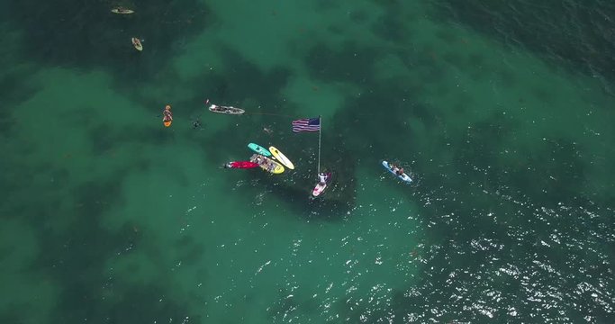 A pan and pull up shot of snorkelers, paddleboarders and kayakers at a local wreck  off the coast.