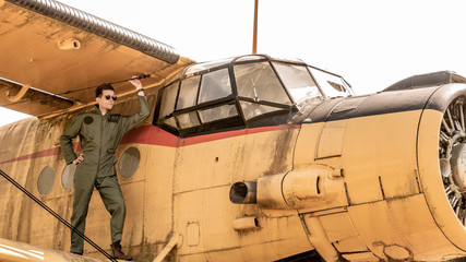 A handsome young pilot standing on the wing of a plane