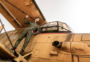 A handsome young pilot standing on the wing of a plane
