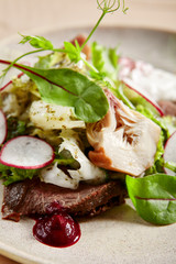 Roast beef, artichokes and poached egg salad in white plate closeup