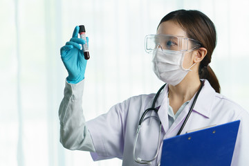 Portrait of a young woman doctor wearing medical mask with stethoscope in uniform, holding Blood...